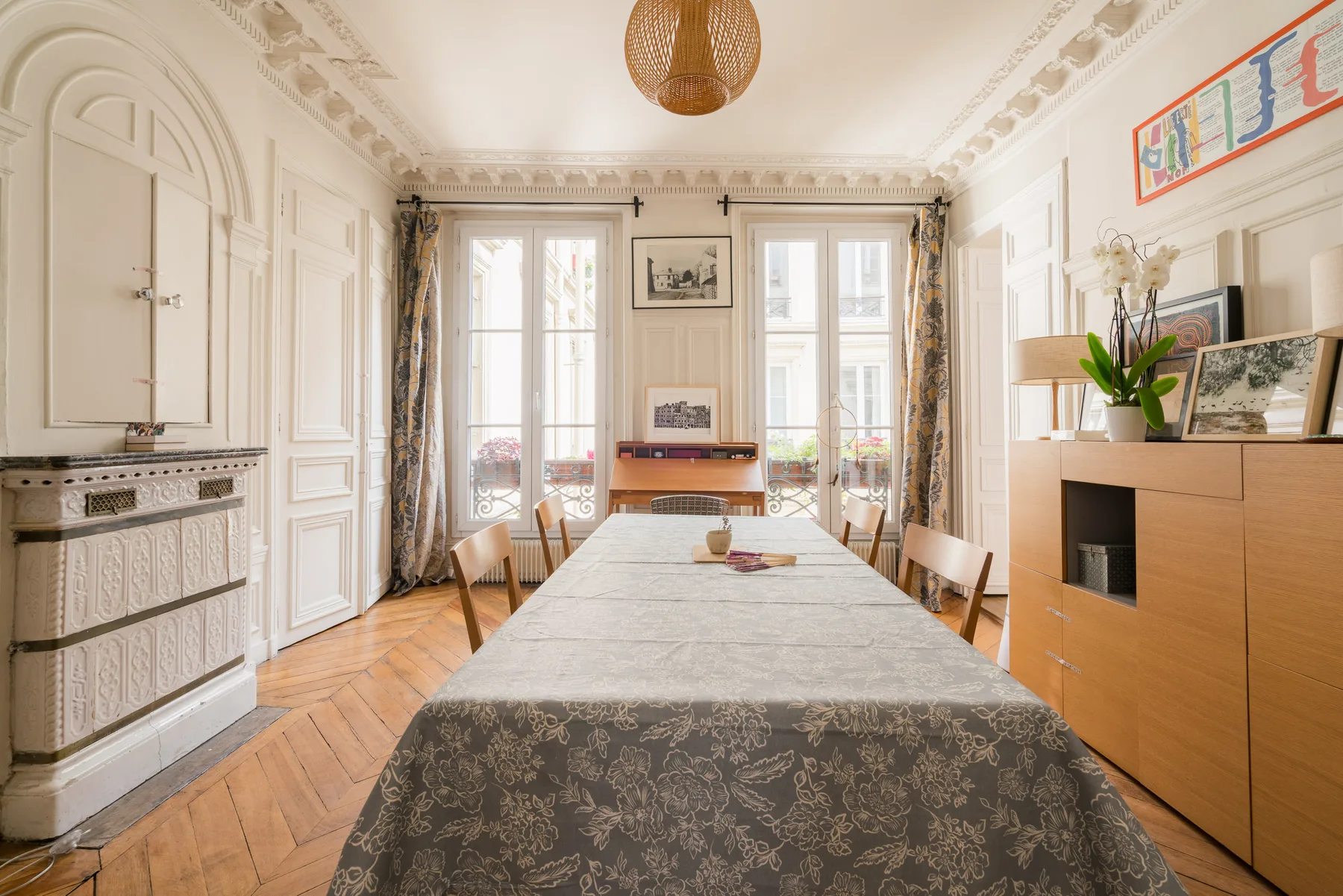 A bright dining room with a long table set in front of tall windows.