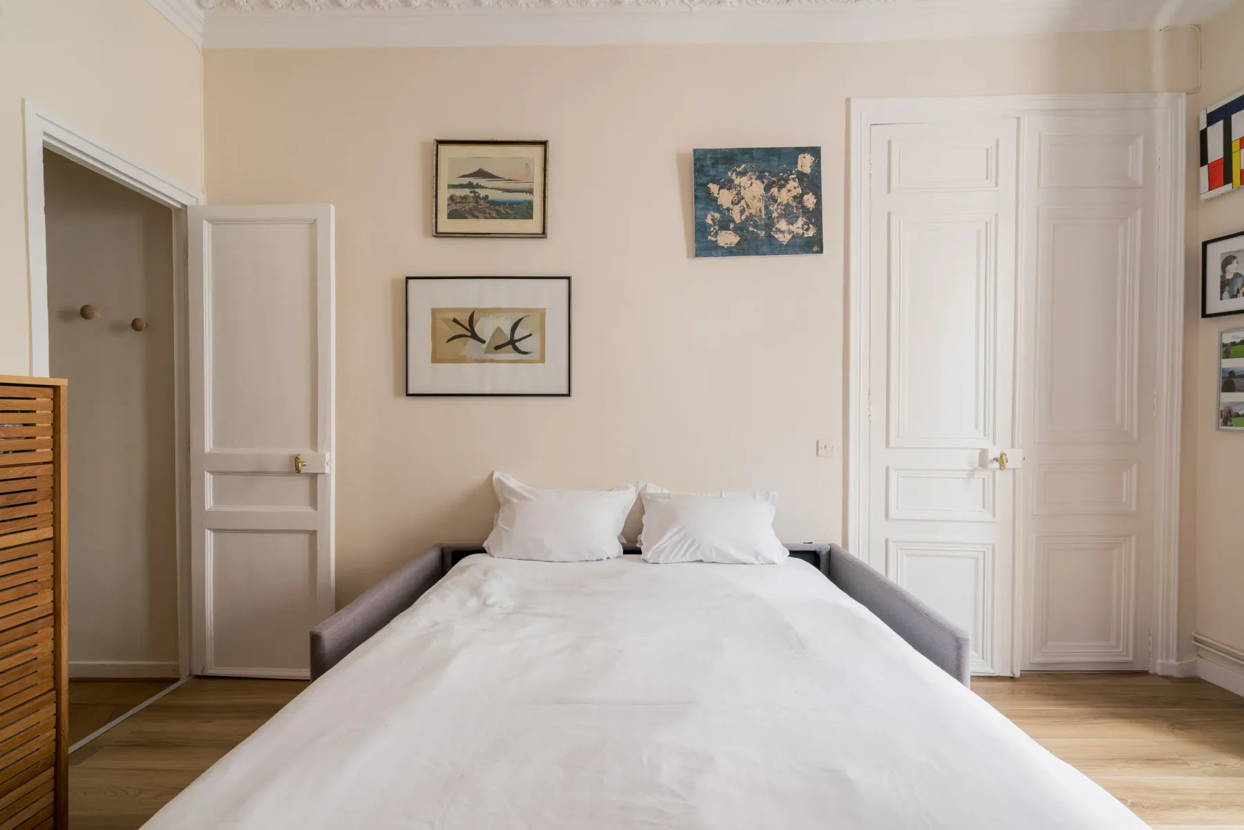 A bedroom with a neatly made bed and framed artwork on the wall.