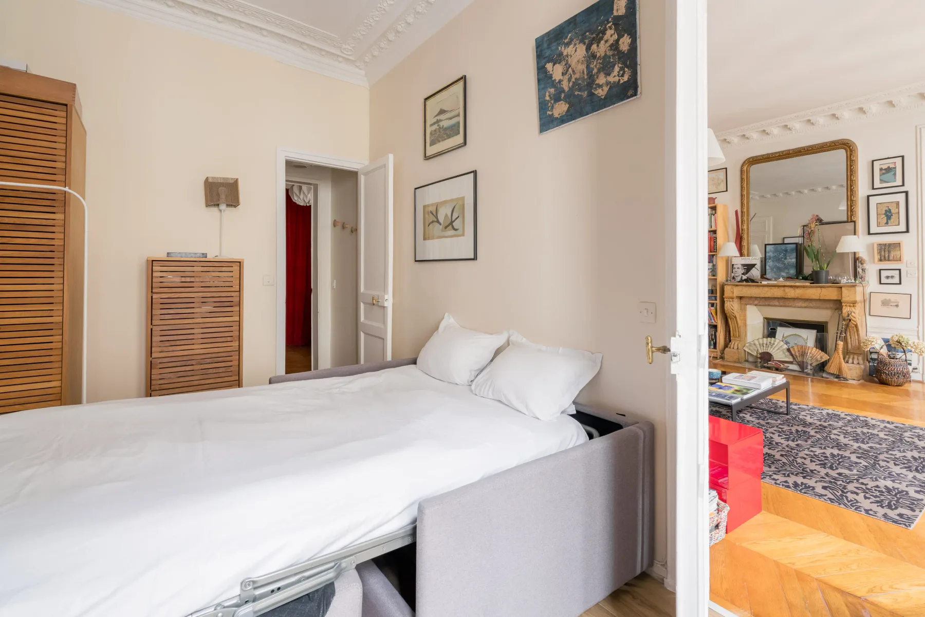 A bedroom with a neatly made bed and framed artwork on the walls.