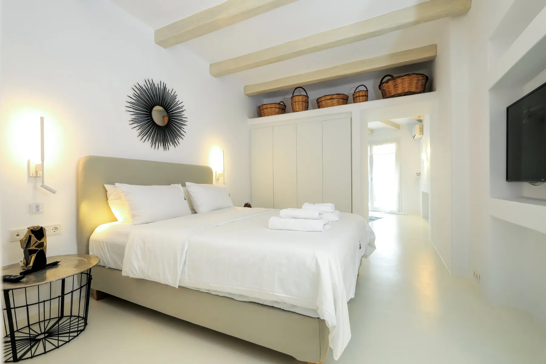 A bright bedroom with a neatly made bed and white linens.