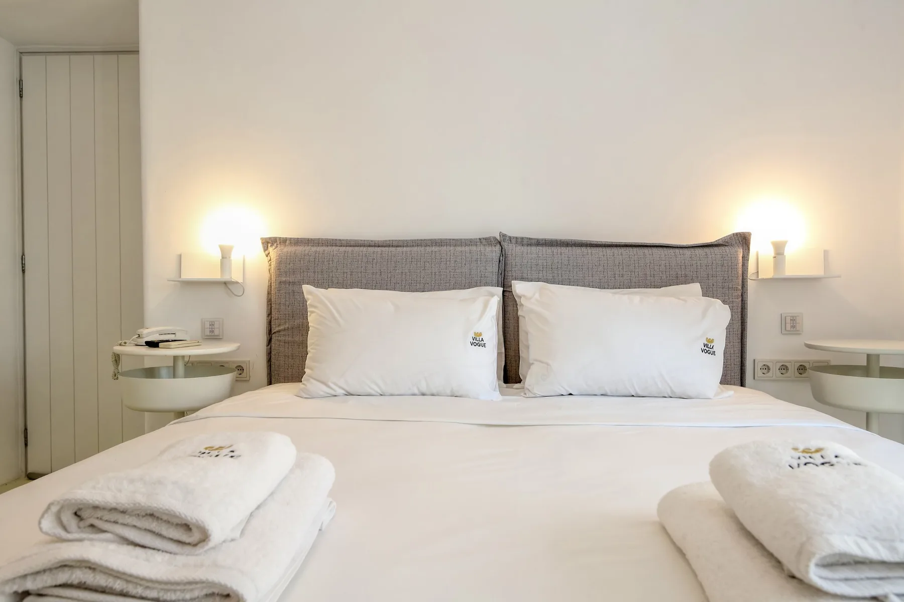 A bedroom with a neatly made bed and matching bedside lights.
