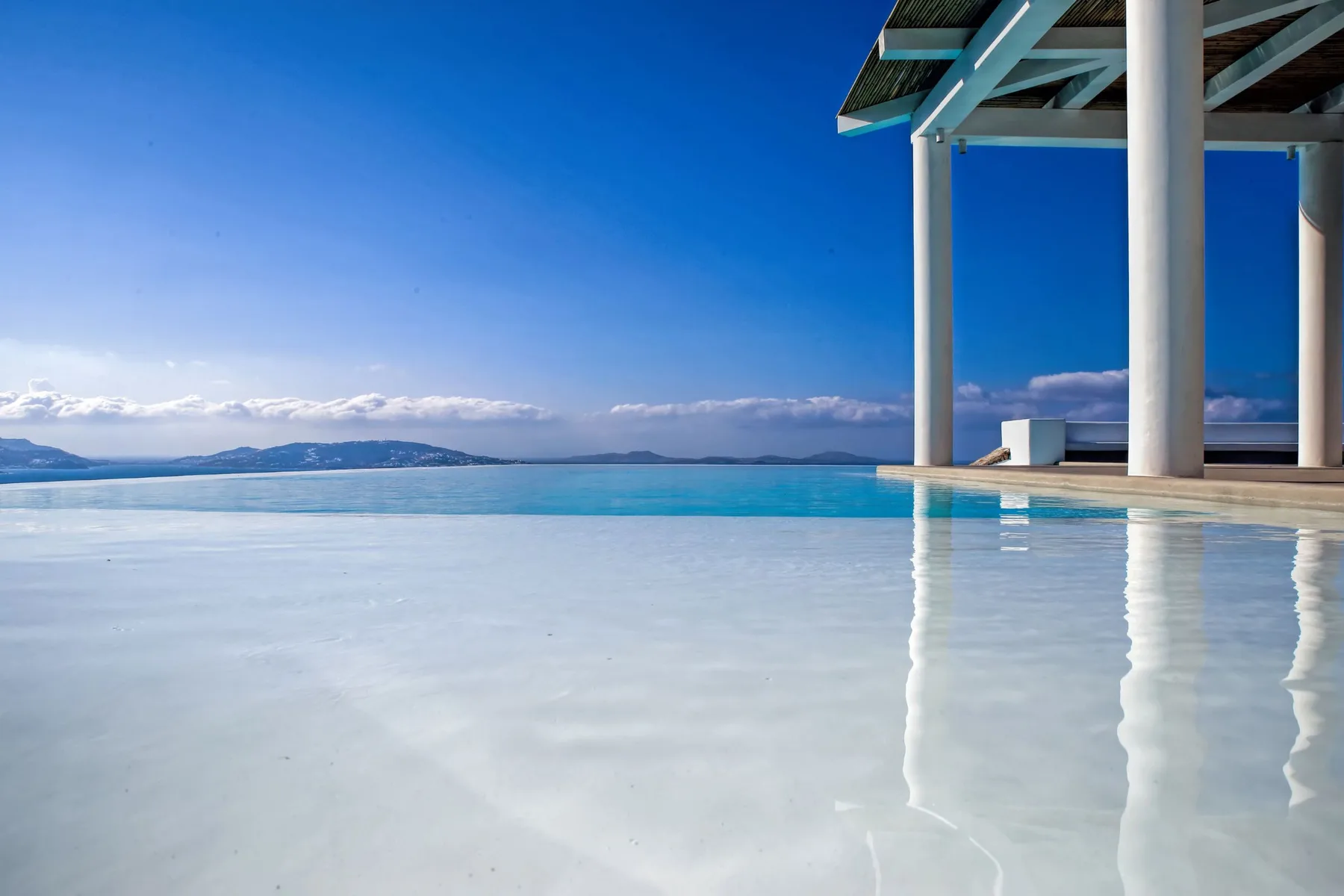 Una piscina poco profunda junto a un patio cubierto mira al mar.