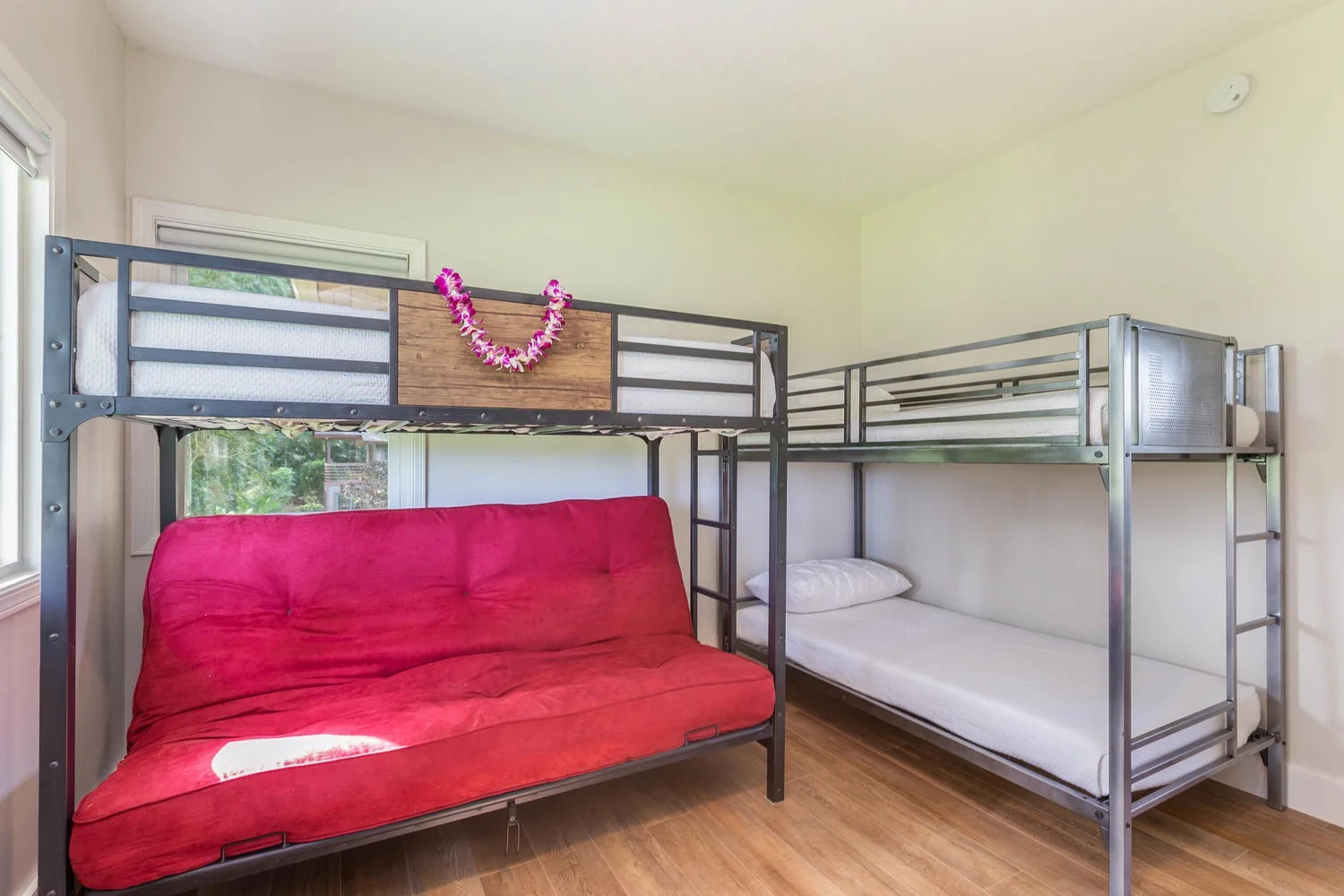 Un dormitorio con literas y un sofá rojo debajo de la cama superior.