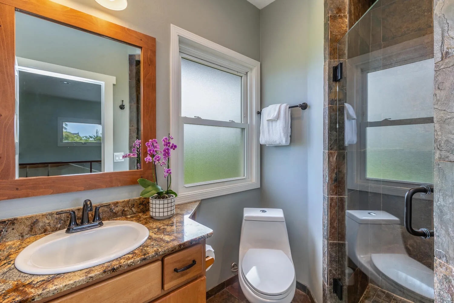 Un baño con lavabo, inodoro, ventana y ducha de vidrio.