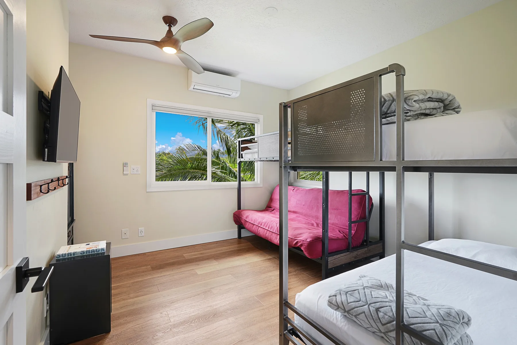 Un dormitorio con literas, un sofá rosa y una ventana con vistas a la vegetación.