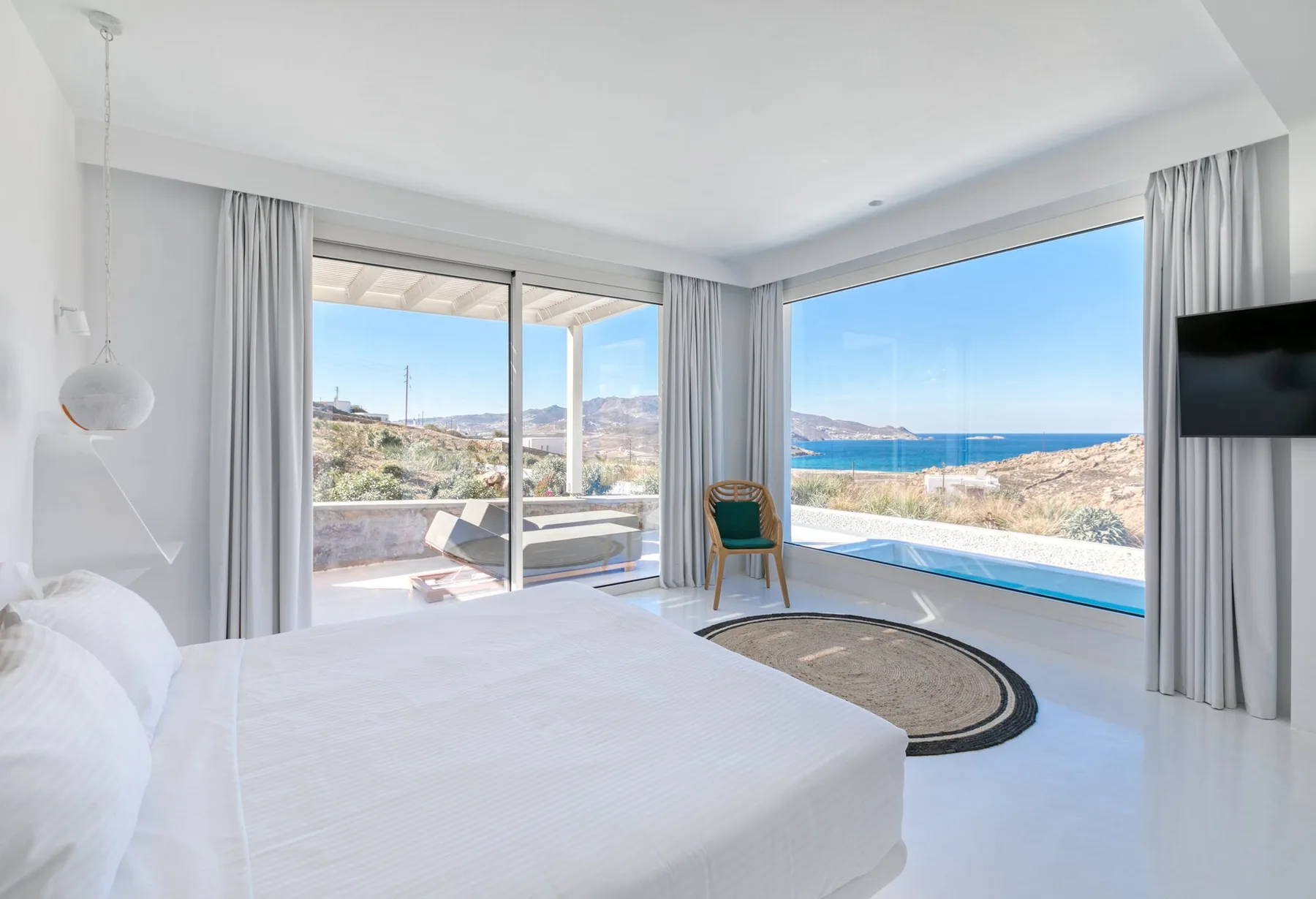 Un dormitorio luminoso da a una terraza con vistas al mar.