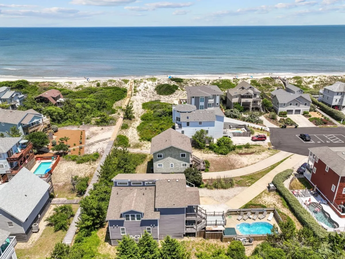 Aerial view of coastal homes and sandy paths beside the ocean.
