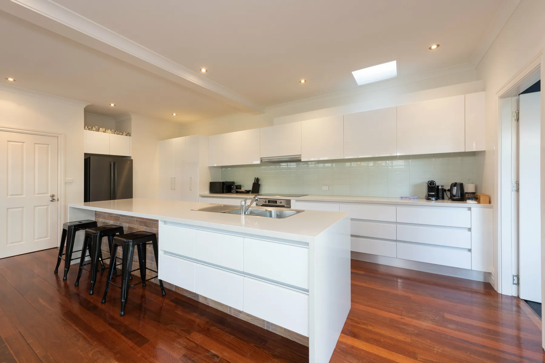 A bright modern kitchen with white cabinetry, a large island, and bar seating.