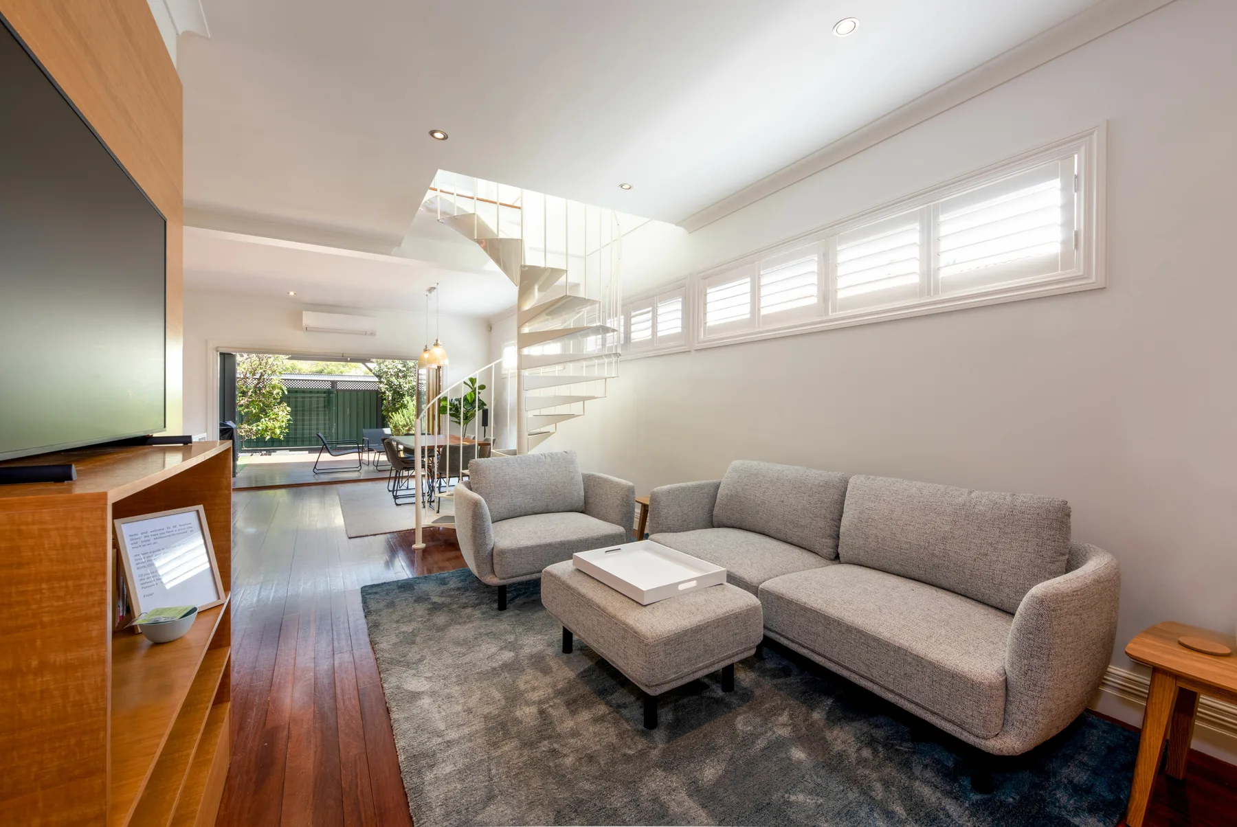A bright living room with seating, a coffee table, and a staircase.