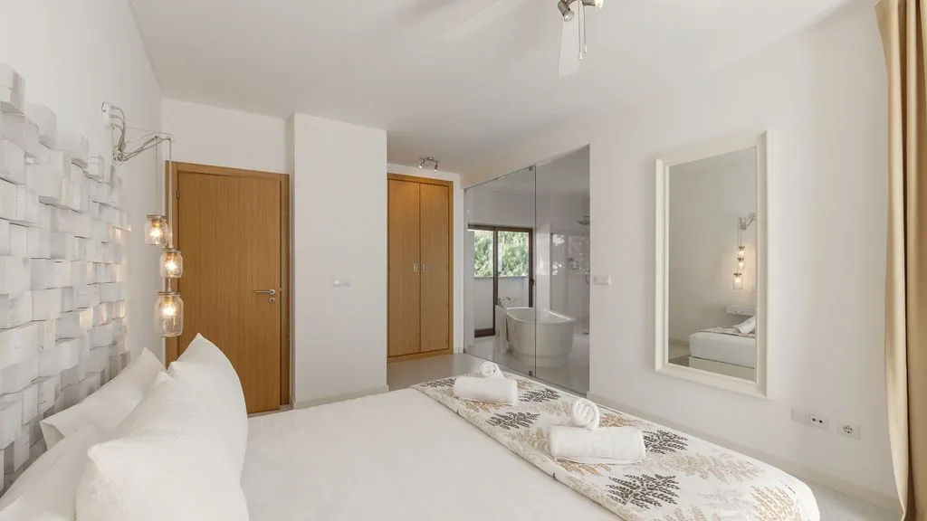 Un dormitorio luminoso con una cama grande y un baño contiguo.