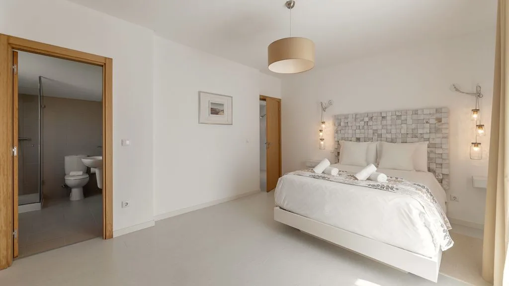 Un dormitorio luminoso con una cama y una pared decorativa de azulejos.