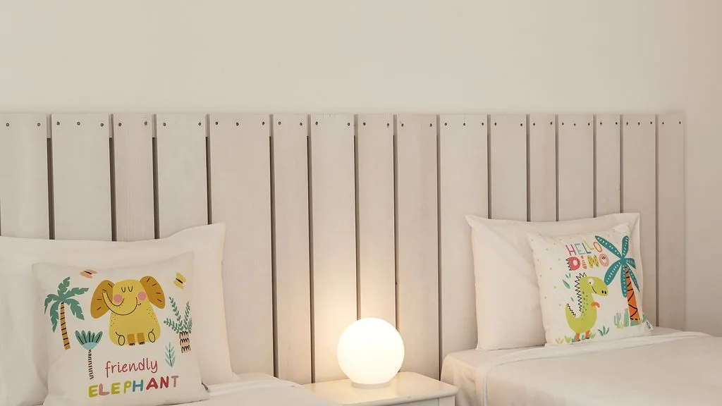 Un dormitorio con una cama, cojines con elefantes y una lámpara encendida.