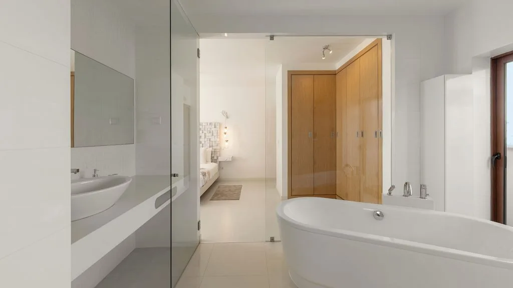 Un baño luminoso cuenta con bañera, lavabo y mampara de ducha de vidrio.