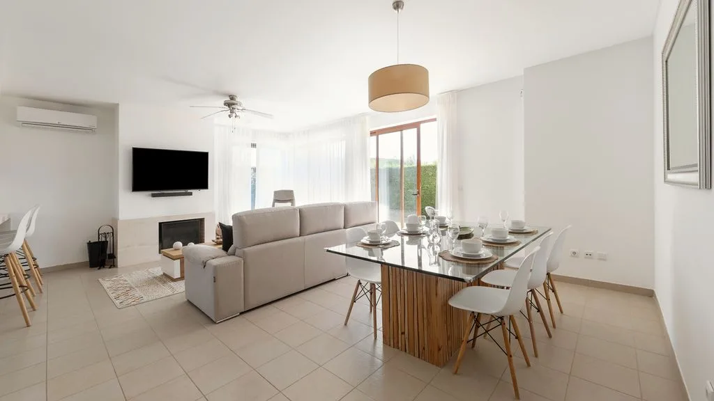 Una luminosa sala de estar y comedor cuenta con asientos, una mesa y ventanas grandes.