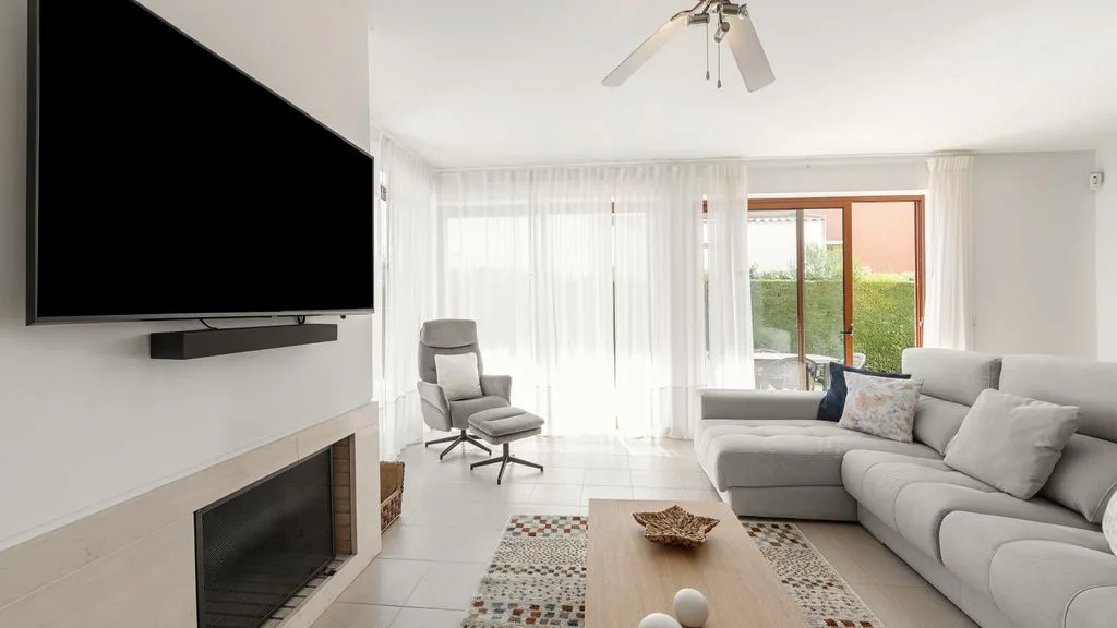 Una sala de estar luminosa con asientos y un televisor montado en la pared.