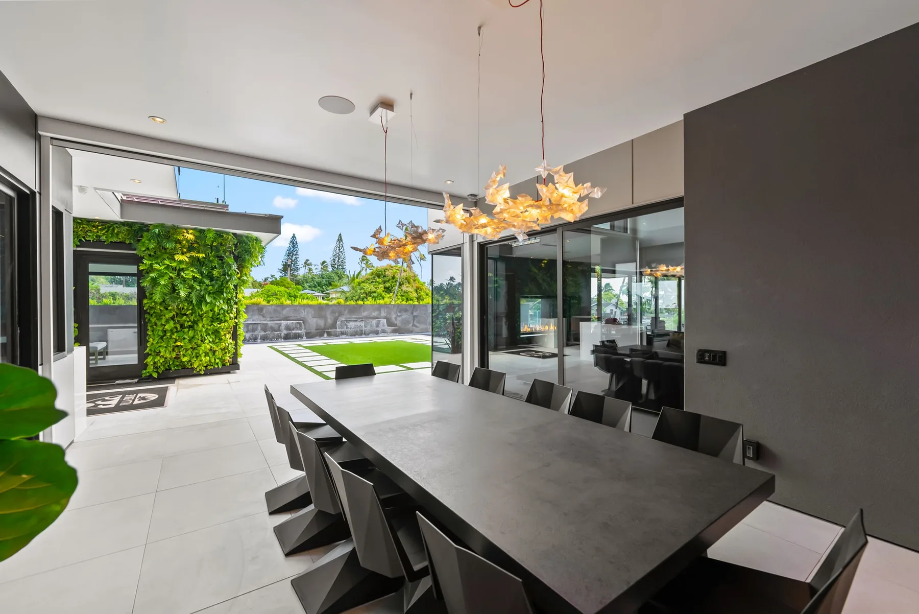 Un comedor moderno con una mesa larga y puertas de vidrio que dan a un patio ajardinado.
