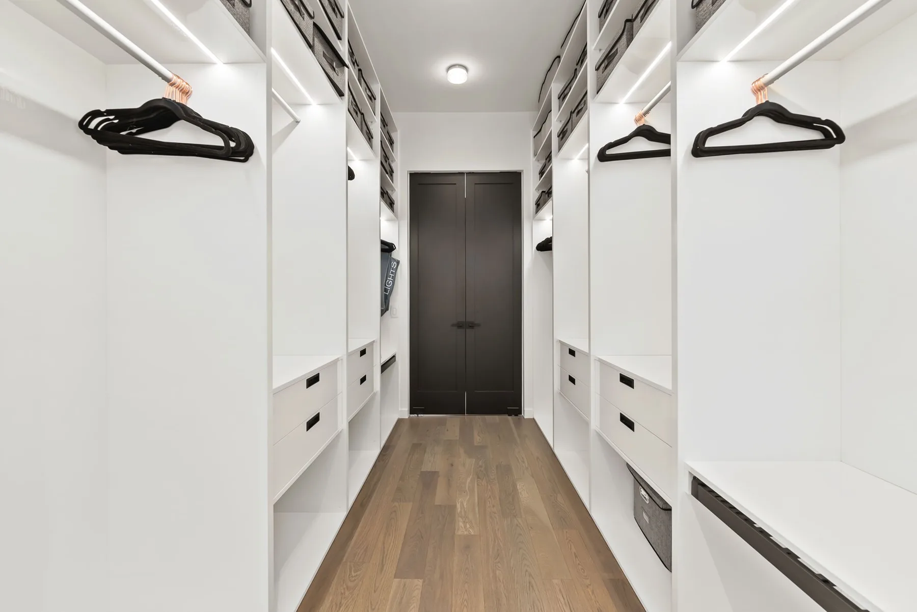 Un vestidor con almacenamiento empotrado blanco y suelo de aspecto madera.