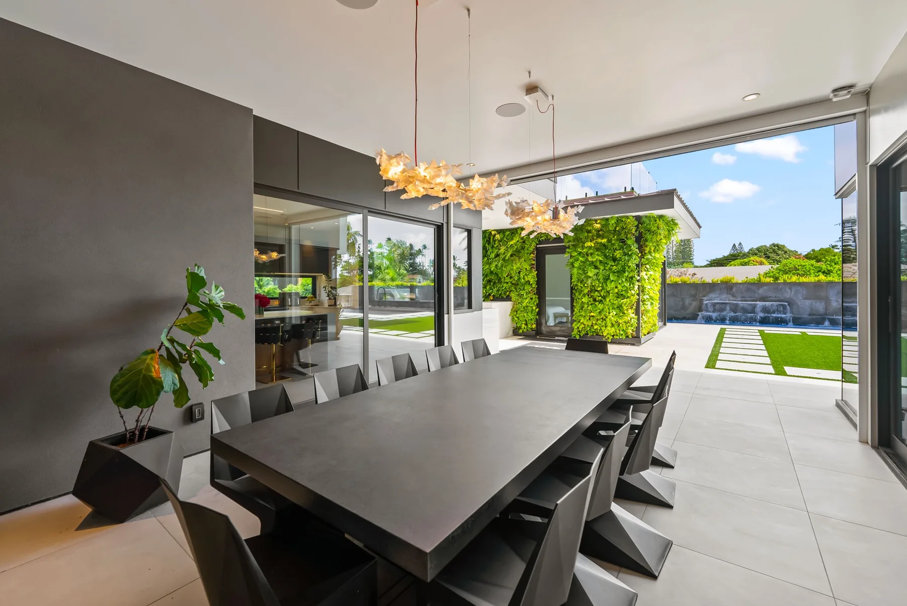 Un comedor moderno se abre a un patio soleado con vegetación.