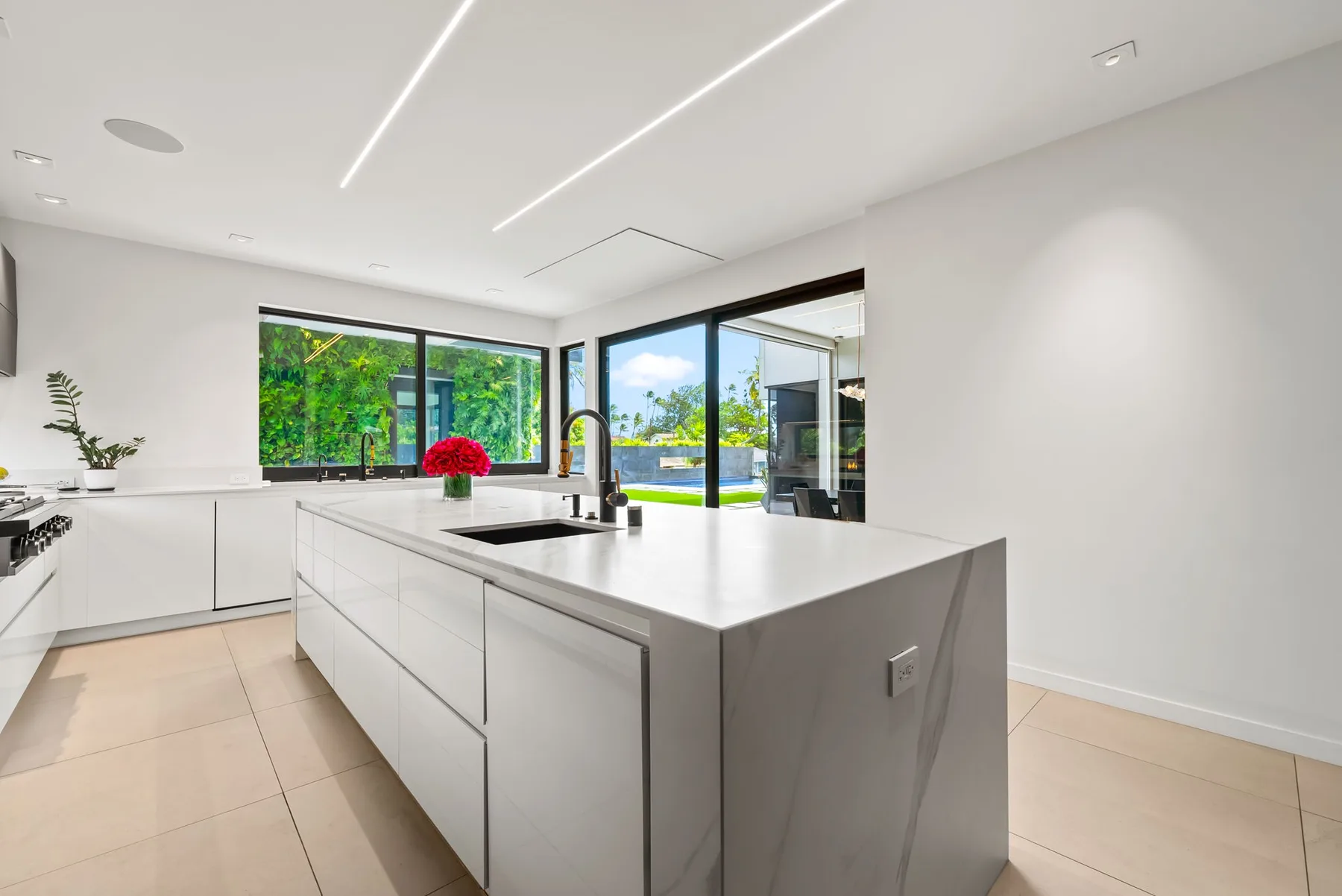 Una cocina moderna y luminosa con una gran isla y ventanas con vistas a la vegetación.