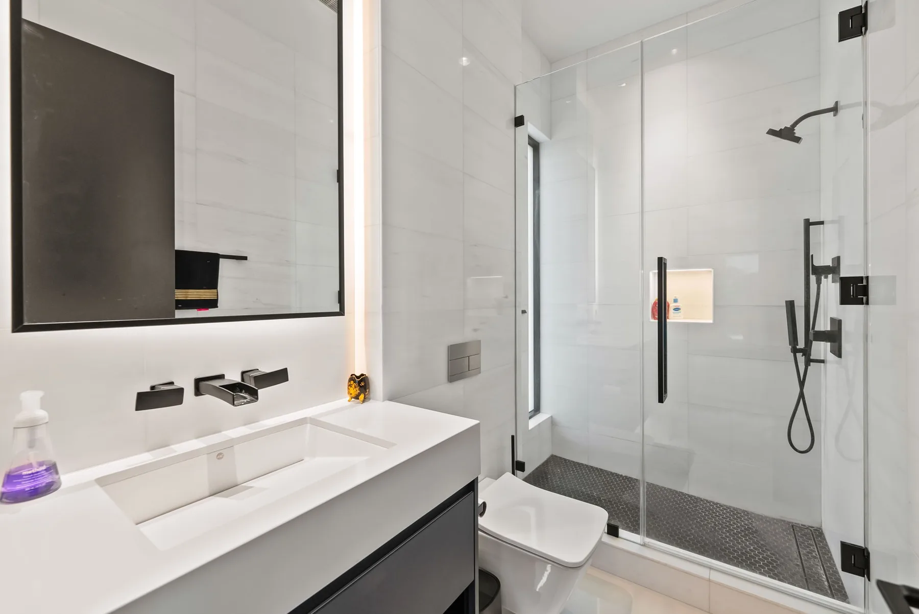 Un baño moderno con lavabo y ducha con mampara de vidrio.