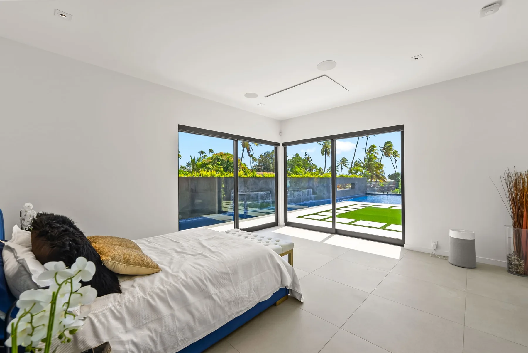 Un dormitorio luminoso con una cama junto a grandes ventanas que dan a un jardín.