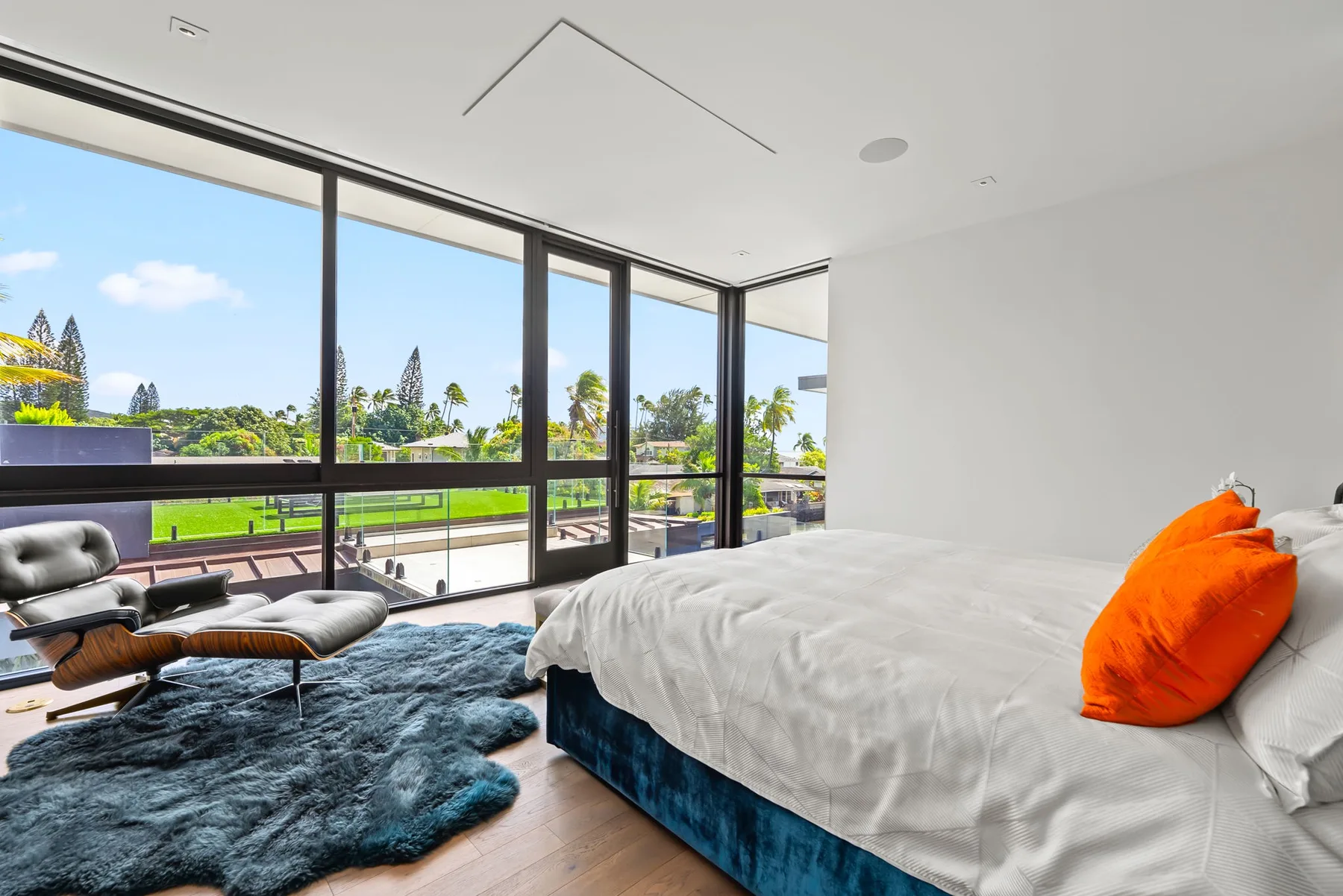 Un dormitorio luminoso con una cama grande junto a ventanales que dan a zonas verdes.
