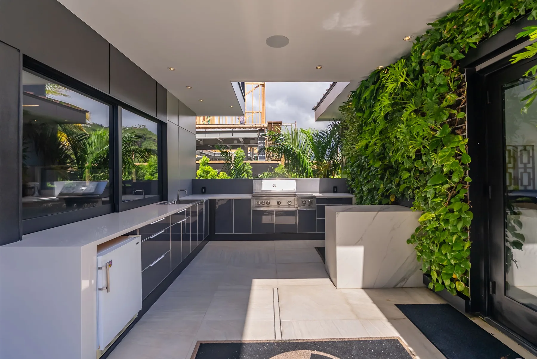 Una cocina al aire libre con una barra y una pared cubierta de vegetación.