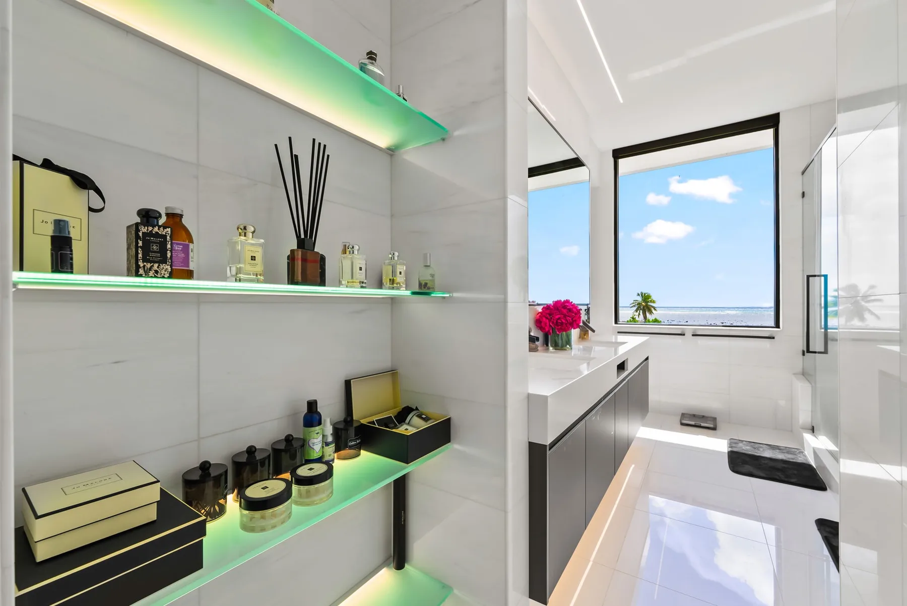 Un baño luminoso con estantes de vidrio, un lavabo y una ventana grande.