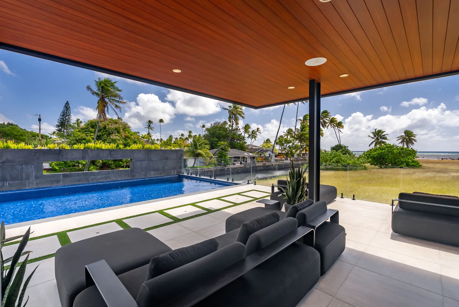 Una sala exterior cubierta da a una piscina y a un jardín.