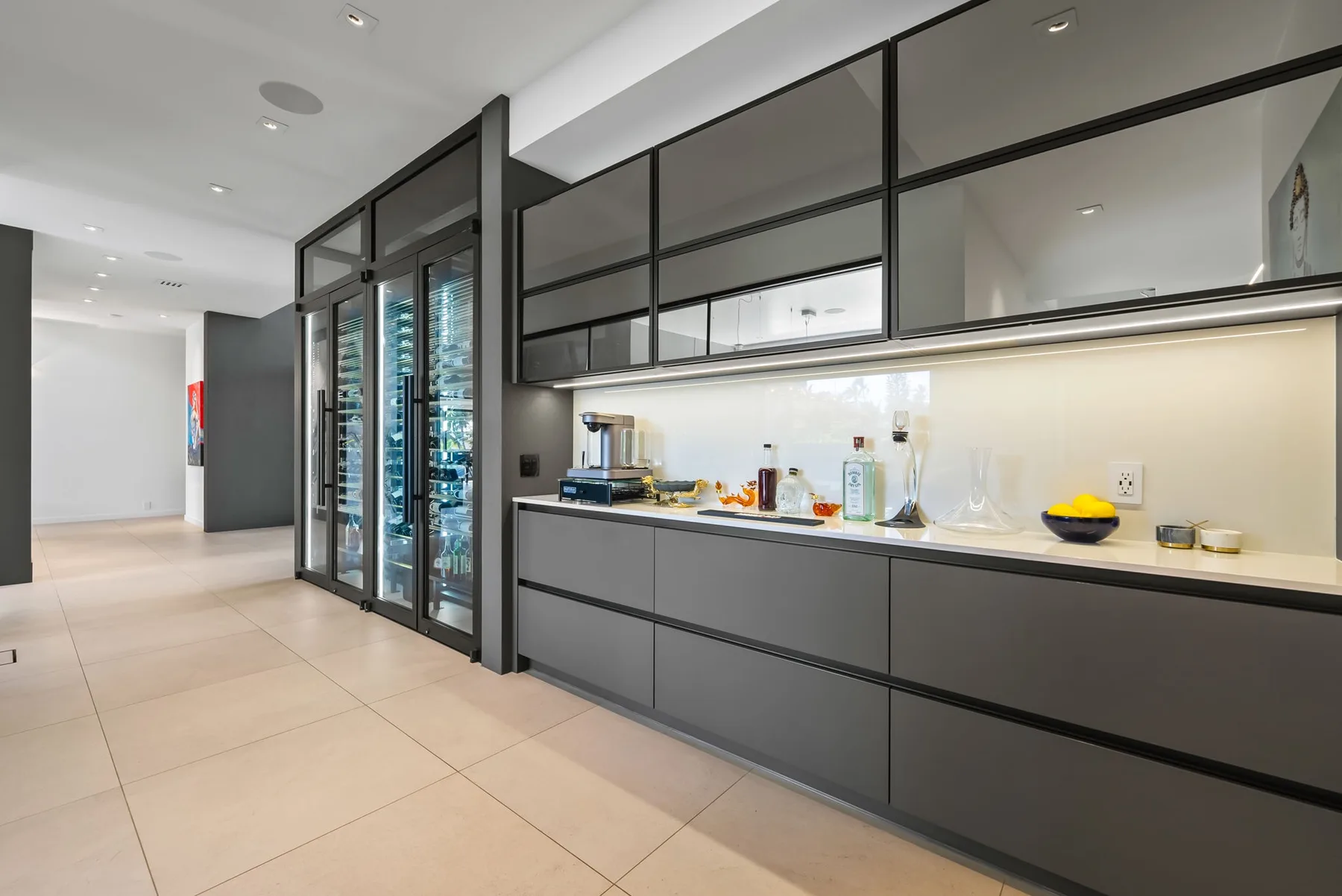Una cocina moderna con armarios oscuros, una encimera y almacenamiento con frentes de vidrio.
