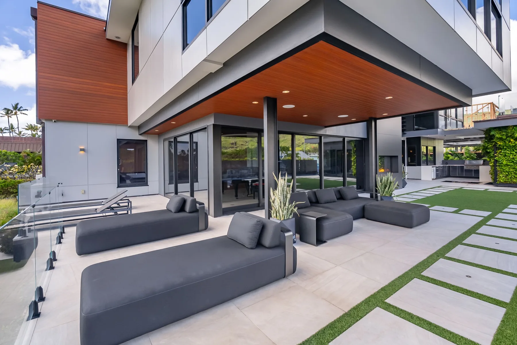 Un patio exterior moderno con asientos bajos bajo un voladizo cubierto.