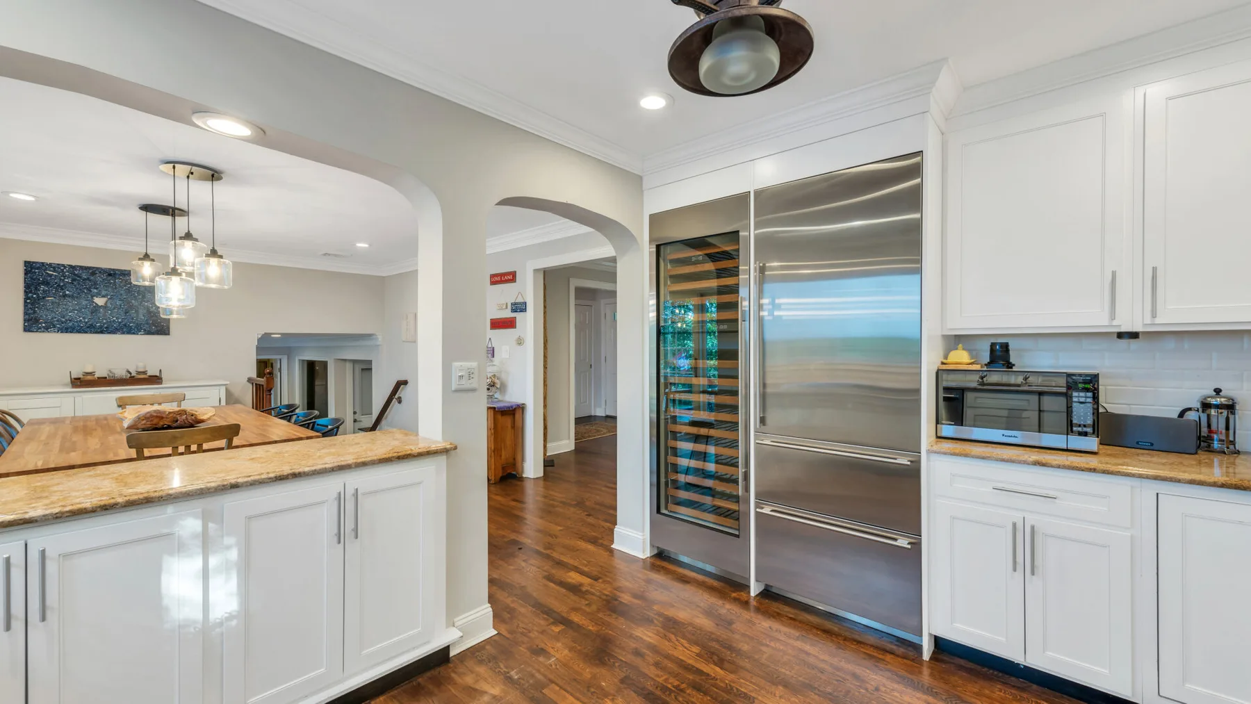 A bright kitchen with white cabinetry, a countertop, and stainless steel appliances.
