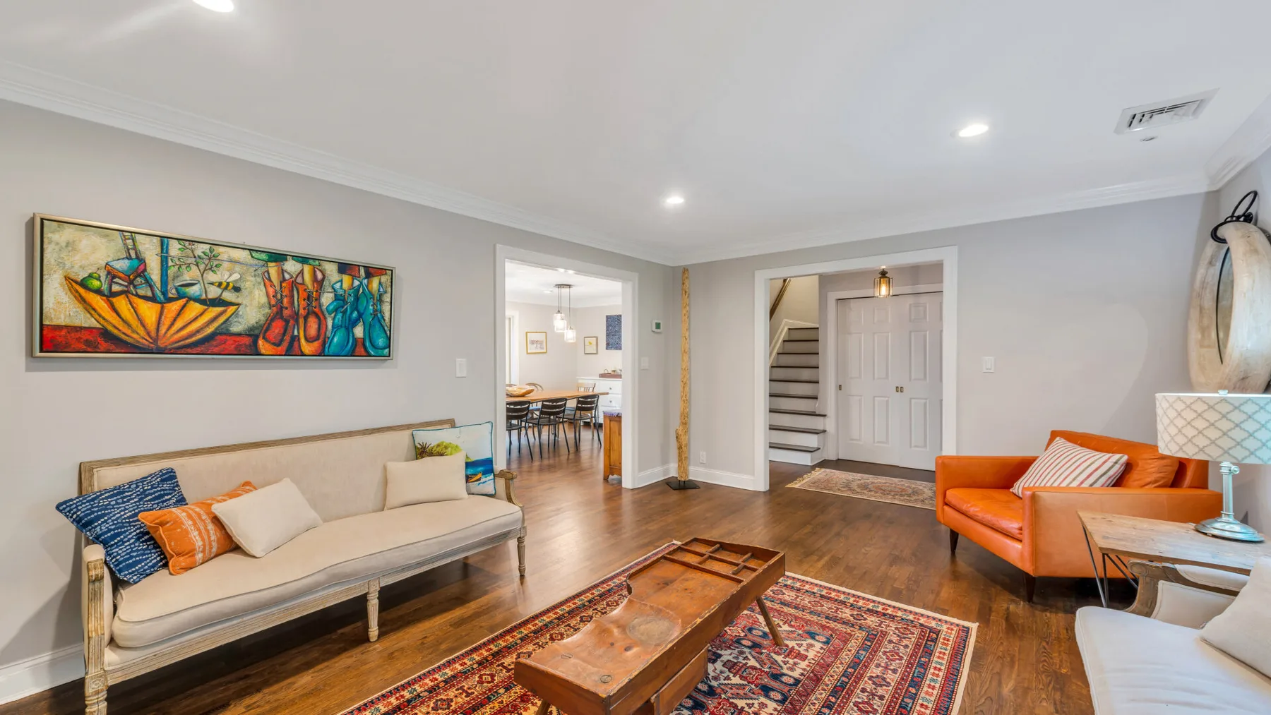 A living room with seating around a wooden coffee table and a colorful rug.