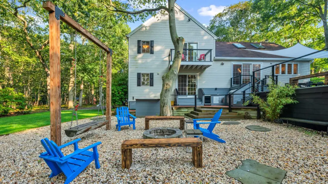 A house opens onto a gravel patio with bright blue outdoor seating.