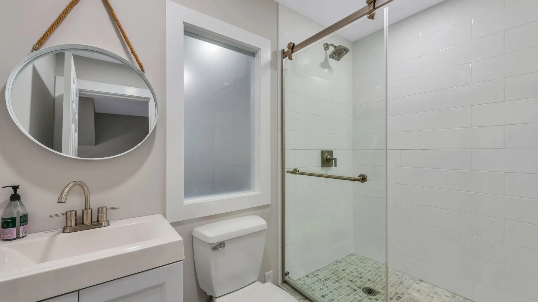 A bathroom with a sink and glass-enclosed shower.