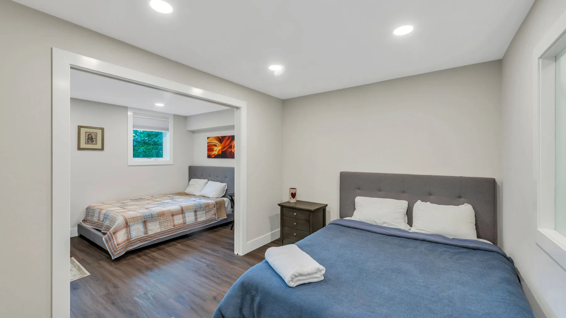 A bedroom with a blue-covered bed and an adjoining sleeping area.