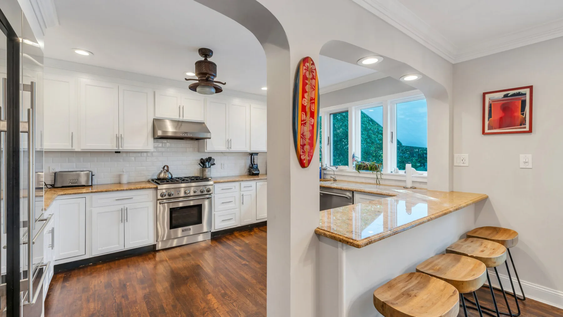 A bright kitchen with white cabinetry and a wood-topped breakfast counter.