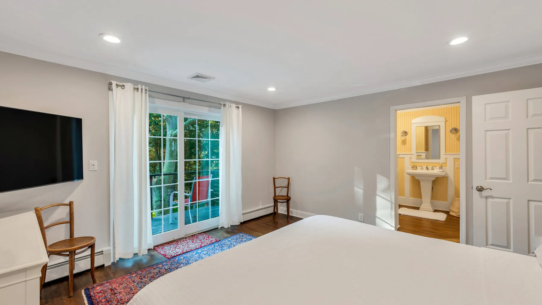 A bedroom with a bed, seating, and glass doors opening to a balcony.