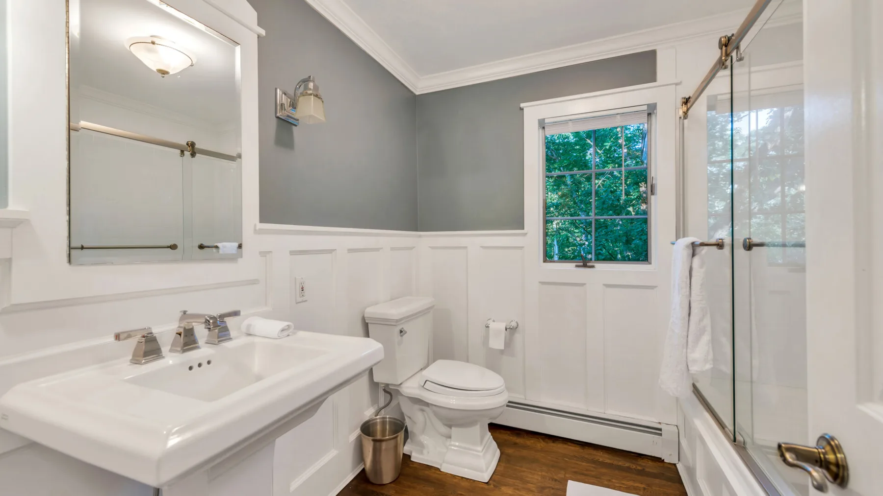 A bathroom with a sink, toilet, and window.