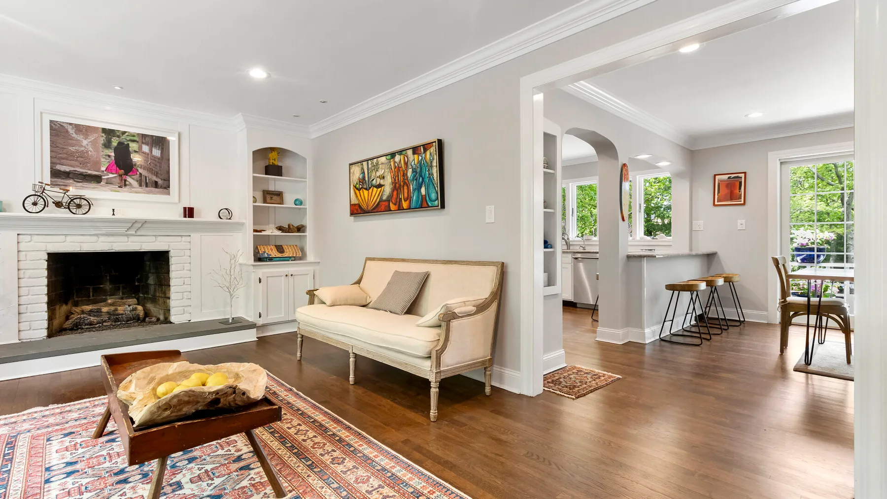 A bright living room with a fireplace, seating, and an open dining area.