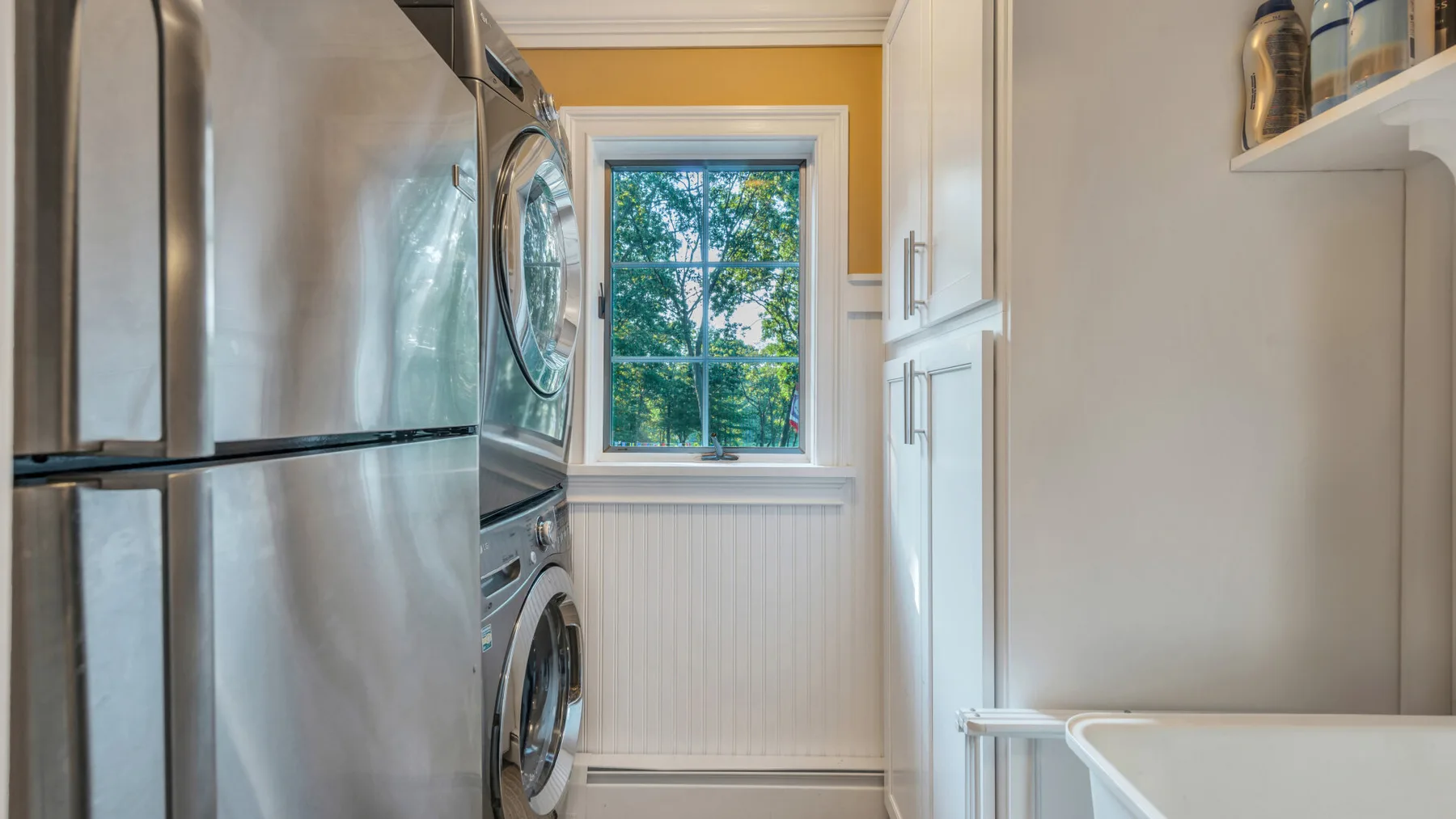 A laundry room with stacked laundry machines beside a window.