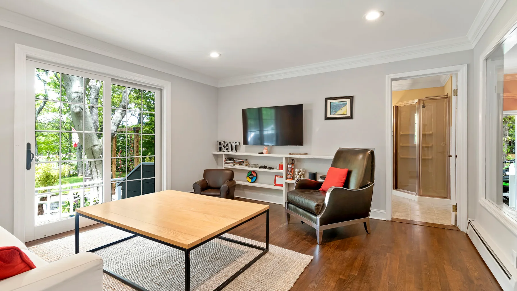 A bright living room with a television, seating, and a wooden coffee table.