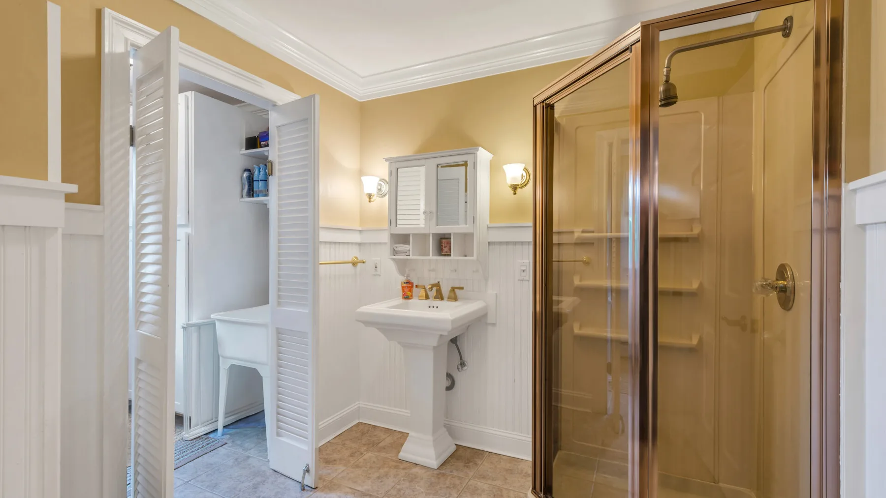 A bathroom with a pedestal sink and a glass shower.
