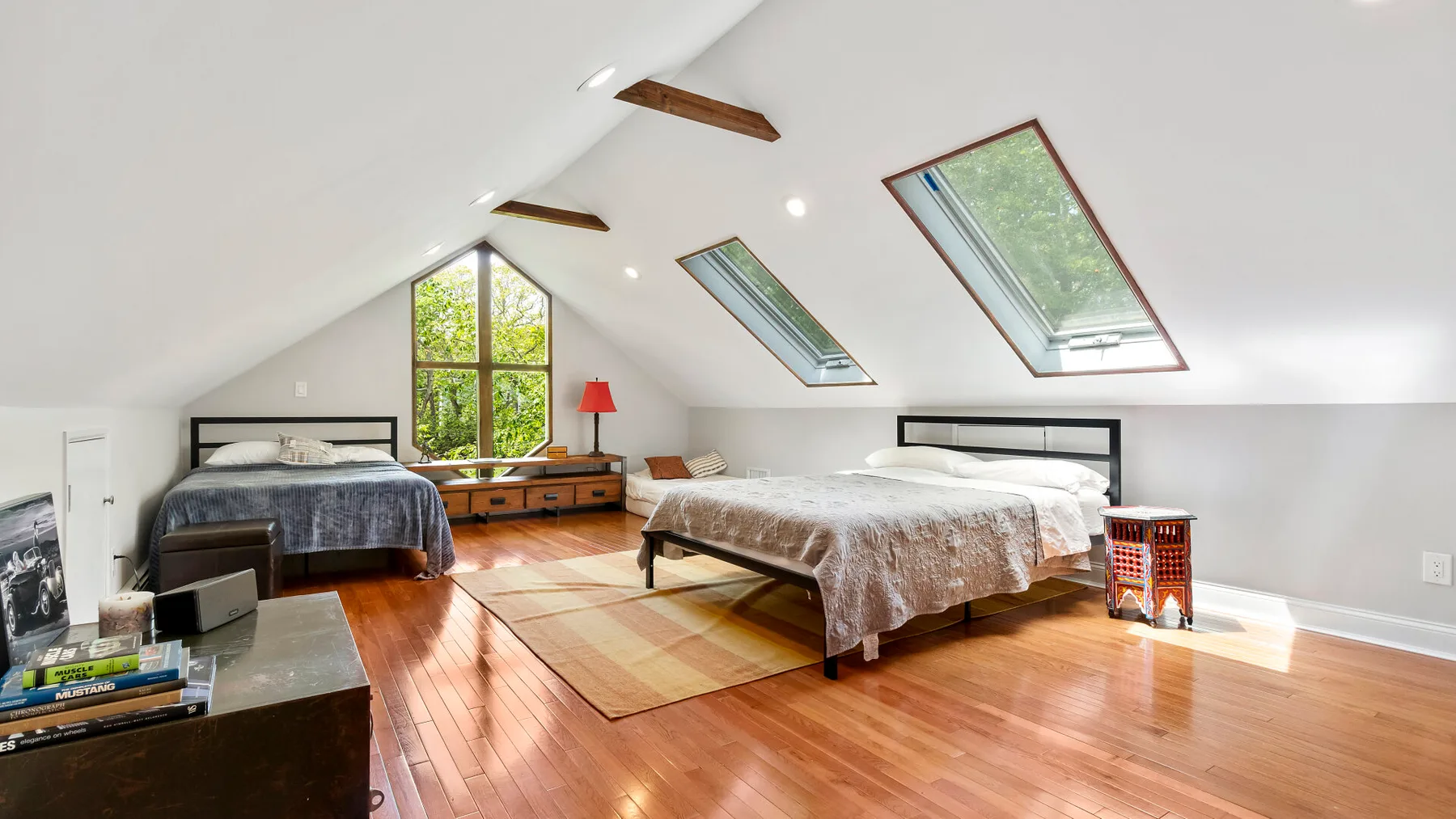 A bright attic bedroom with two beds beneath sloped ceilings and skylights.