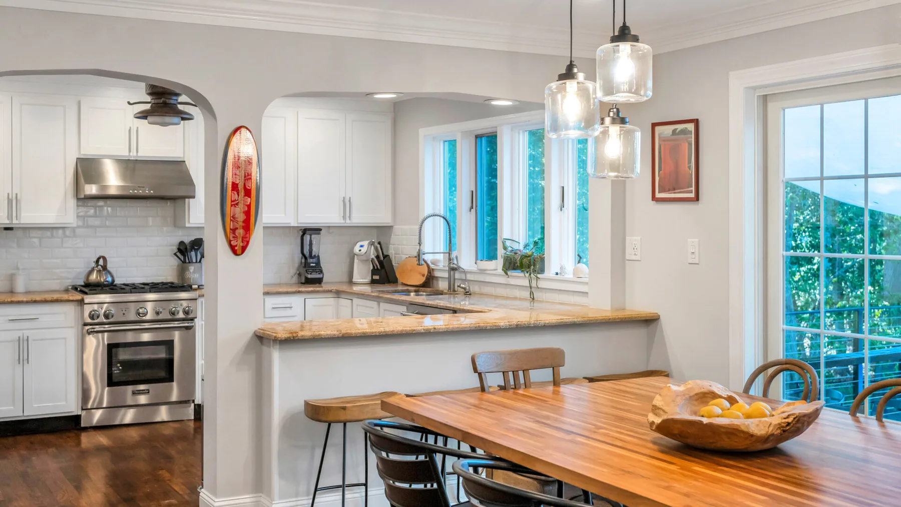 A bright kitchen and dining area with a wooden table beside the counter.