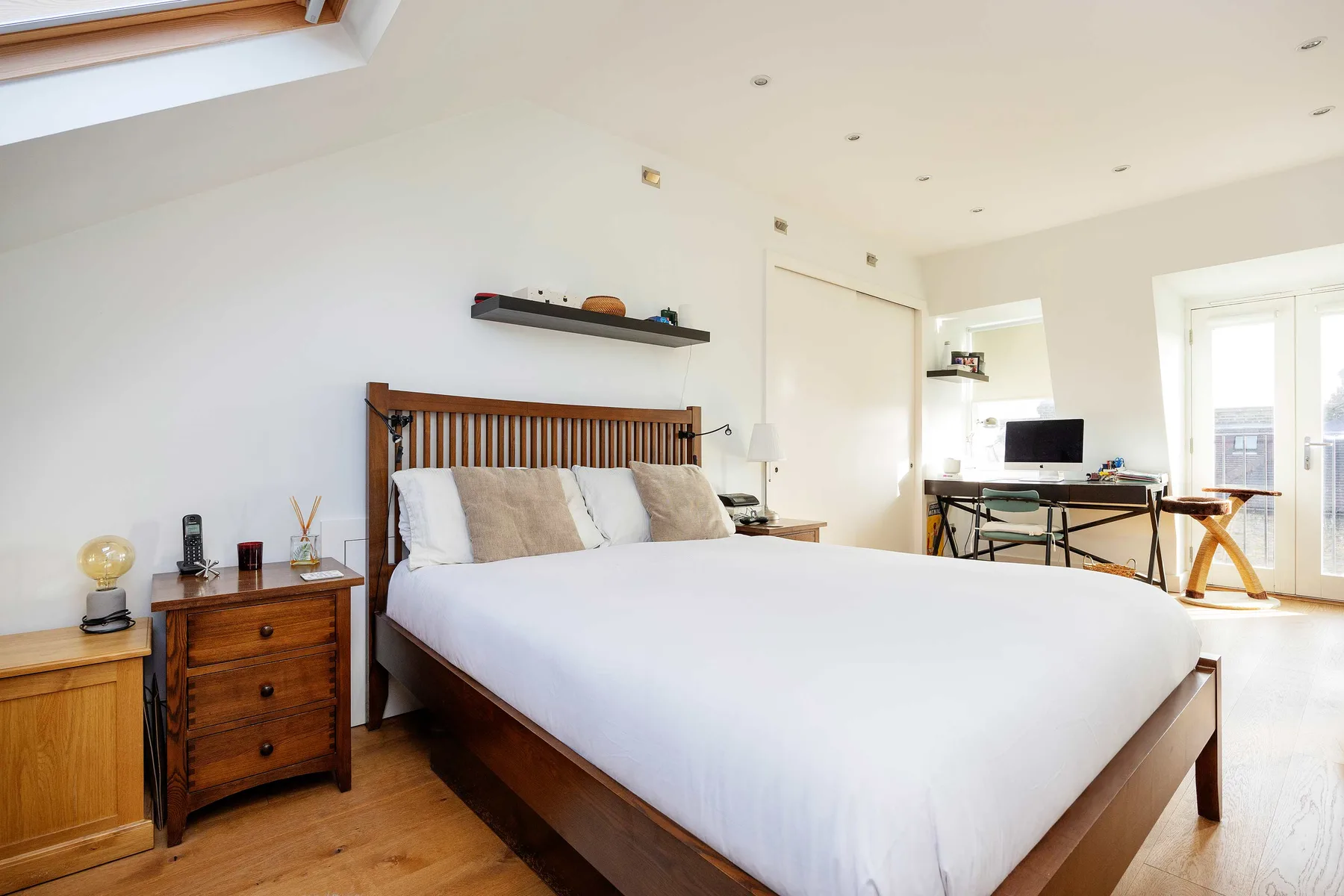 A bright bedroom with a large bed and a desk by the windows.