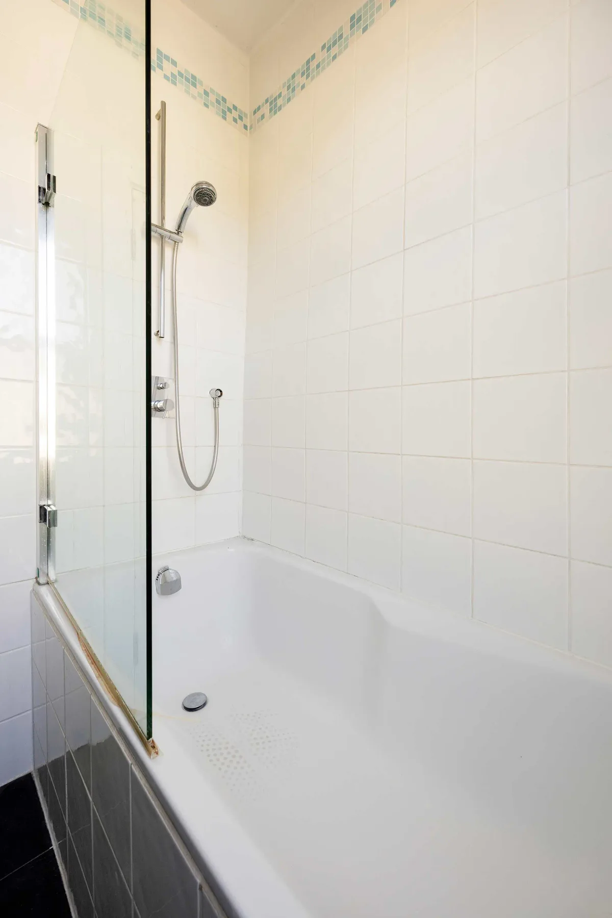 Un baño alicatado con bañera y ducha de mano.