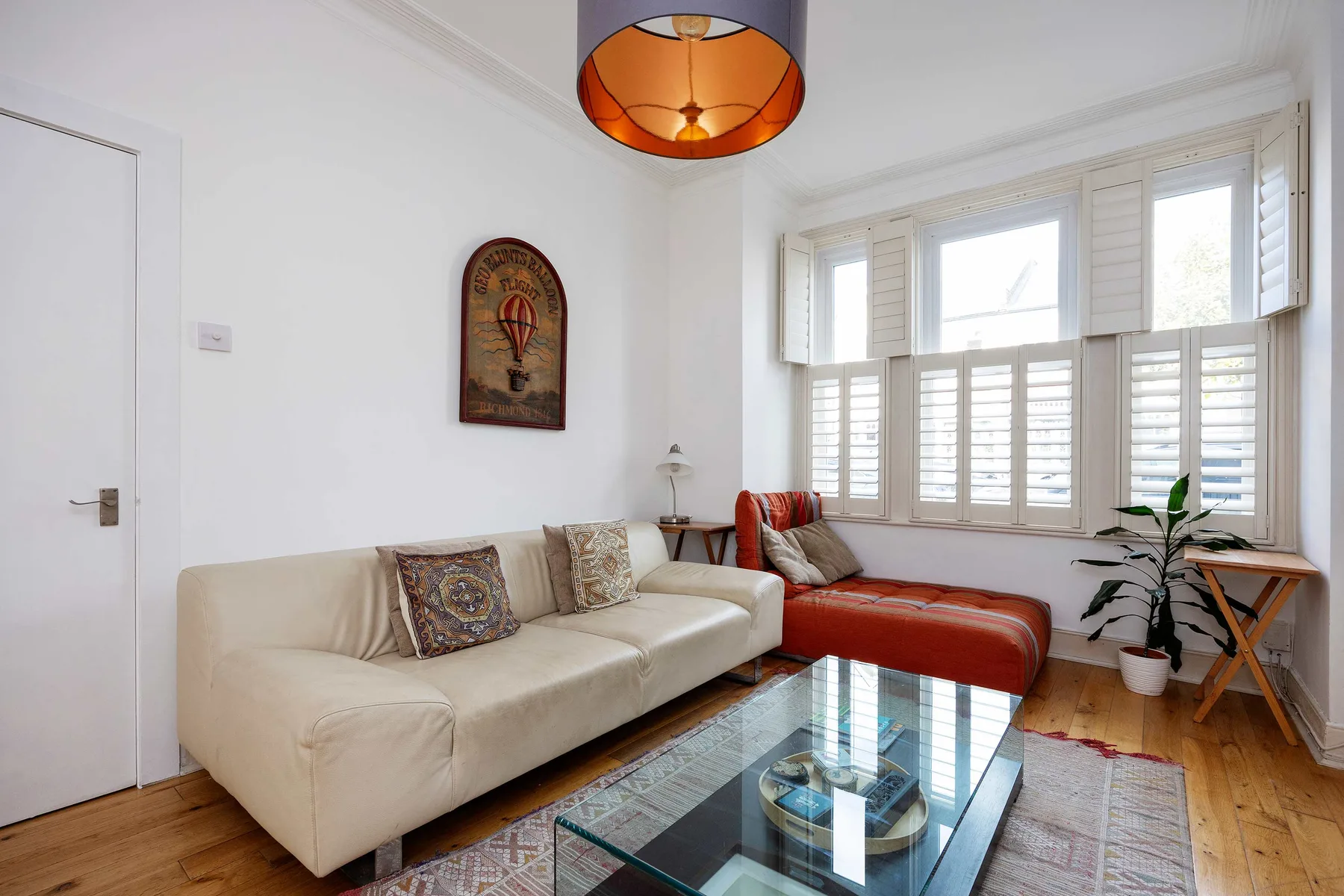 A bright living room with a cream sofa and large windows.