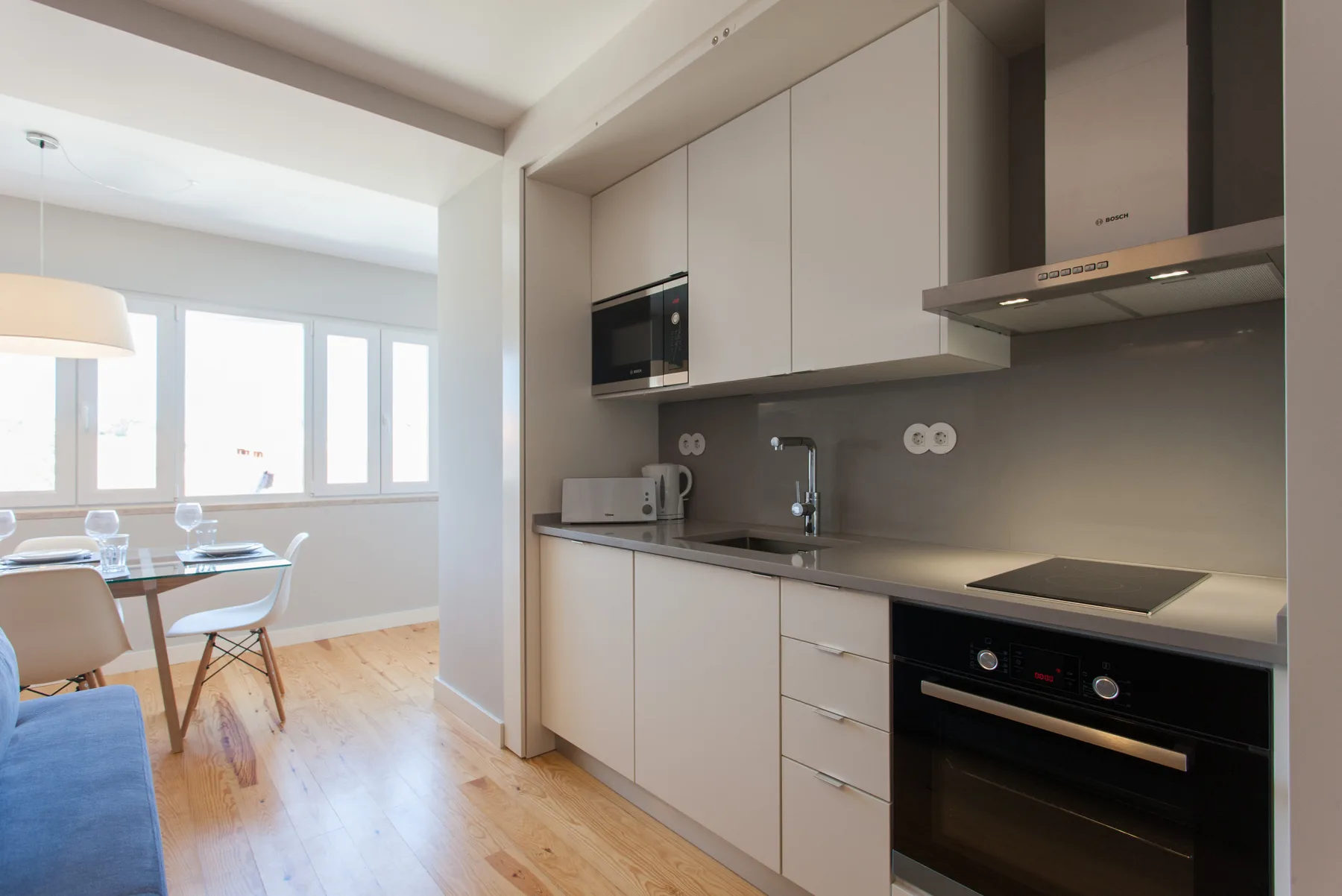 Una cocina moderna se abre a una zona de comedor con mesa y sillas.