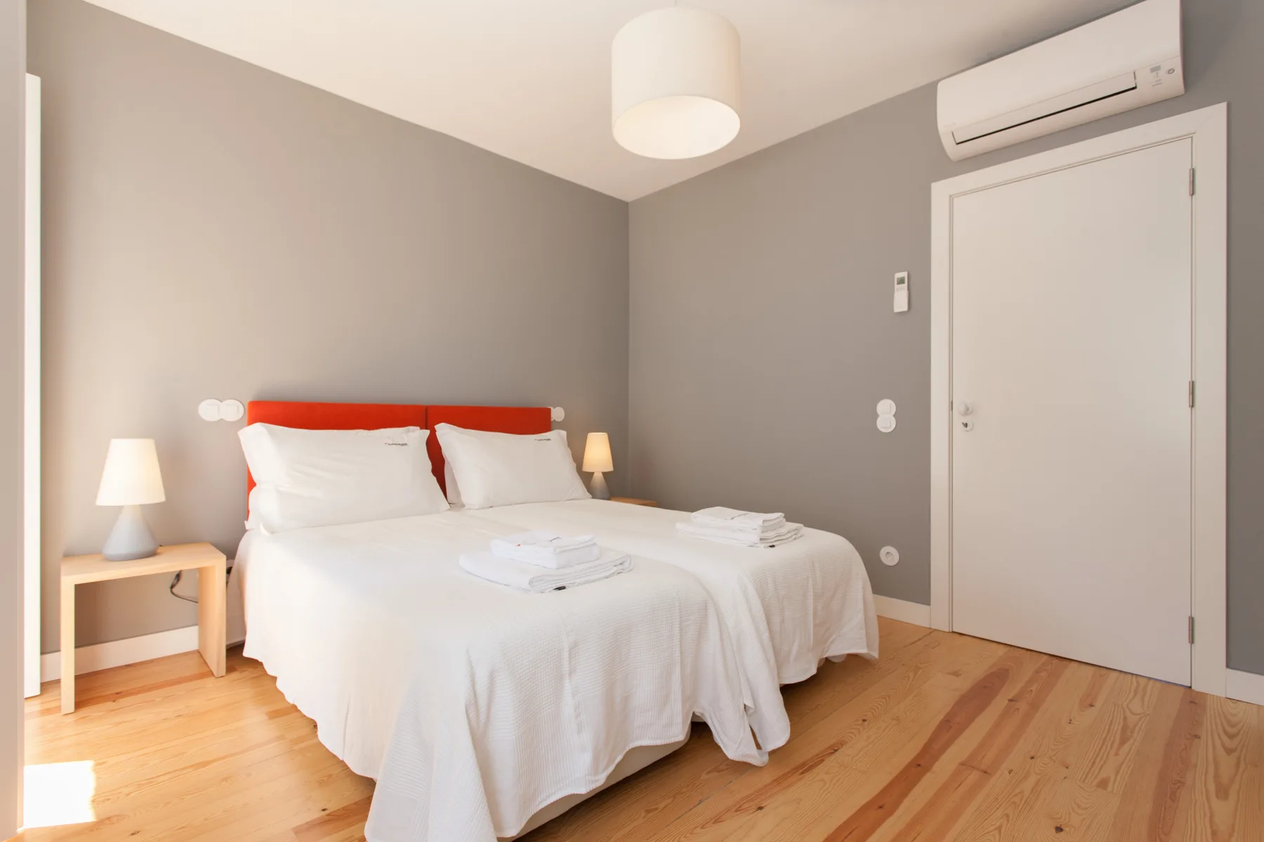 Un dormitorio con una cama bien tendida y suelo de madera.